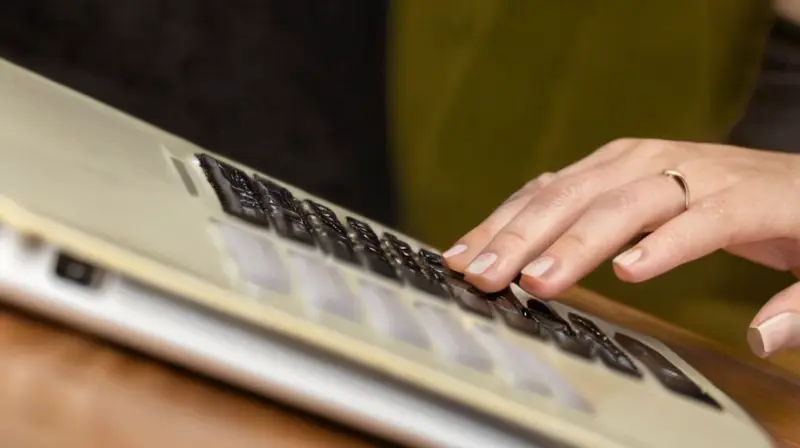 Una mujer sentada en un sofá, rodeada de desorden, busca información efectiva para prepararse para oposiciones estudiando en su tablet