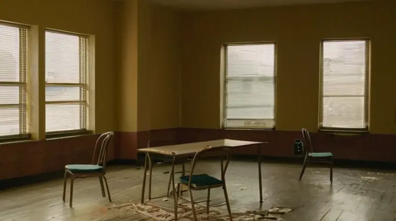 El cuarto pequeño está iluminado sólo débilmente, con un estilo desorganizado debido a la presencia de colchas, papeles y útiles escolares sobre una mesa